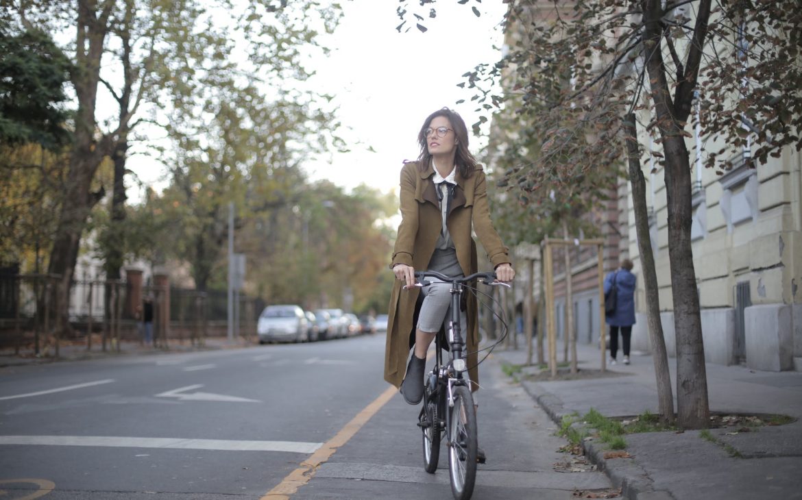 woman in brown coat riding a bicycle PERFECT BAG