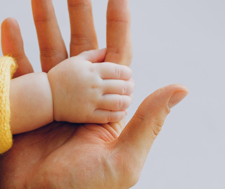 person holding babys hand Gender-neutral baby names offer a beautiful way to celebrate individuality and inclusivity.