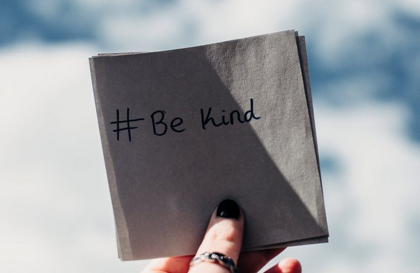 person holding note with be kind text